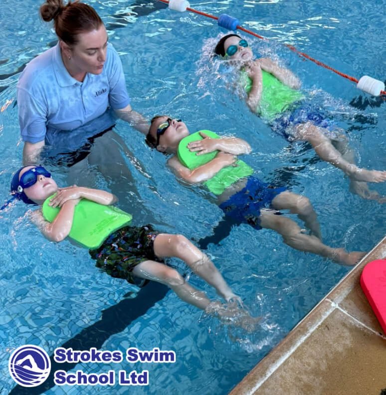 Children learning backstroke with green floats at swimming lesson