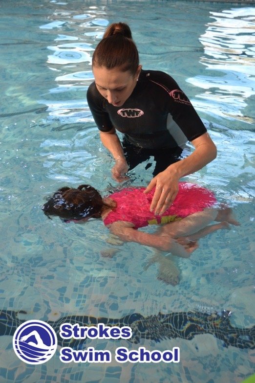 Instructor teaching backstroke to girl in the pool