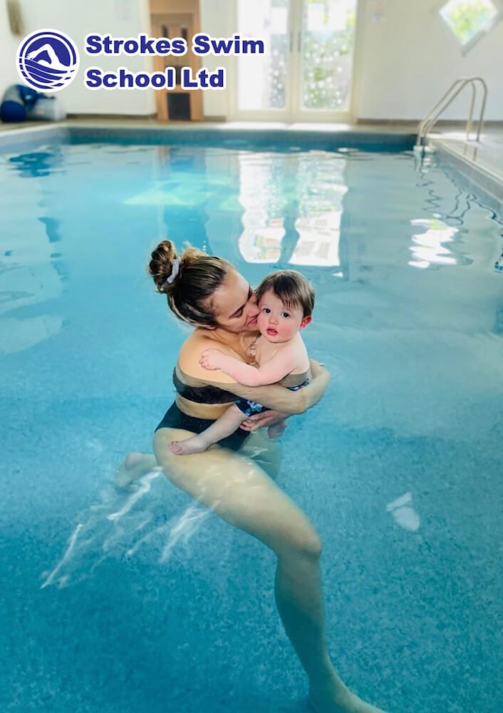 Mum kissing baby in the swimming pool