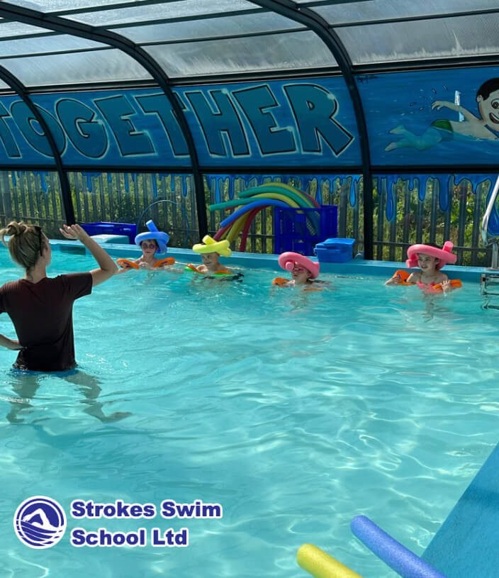 Children wearing fun hats during outdoor swimming lesson