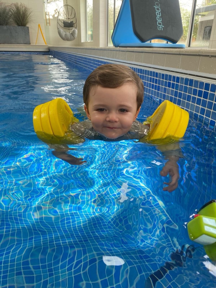 Toddler with yellow armbands in boutique swimming pool