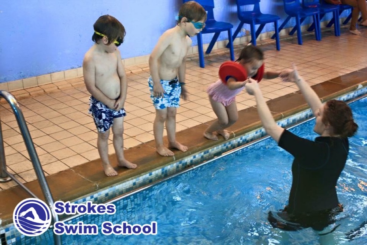 Children jumping into the pool during swimming lesson at Sweyne School