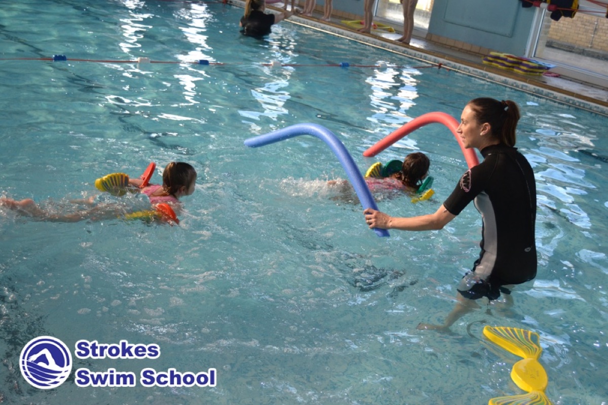 Swimming teacher with pool noodles teaching children at Sweyne School